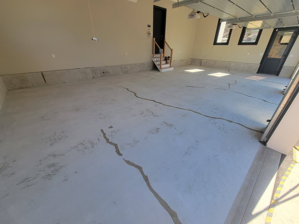 Large garage concrete floor with deep cracks before epoxy coating