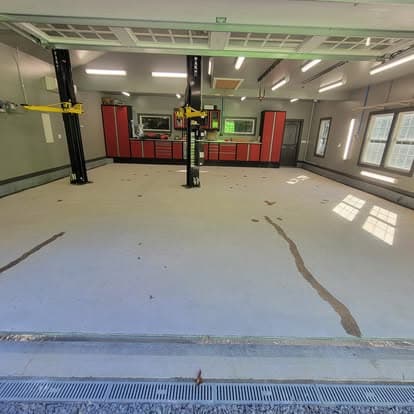 Car shop with two-post lift and cracked concrete floor before metallic epoxy